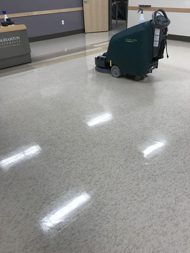 Lavadora automatica trabalhando em area interna com piso brilhante.